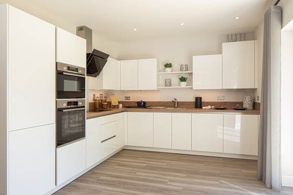 A modern kitchen with white cabinets and a wooden floor.