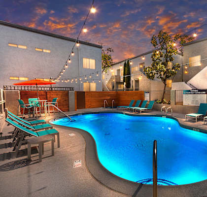 a swimming pool with lounge chairs and umbrellas in front of a building