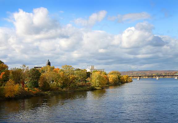 A river flows through a city with a church on an island in the middle.