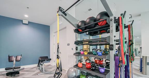 A gym with a variety of equipment including kettlebells, resistance bands, and a cable machine.