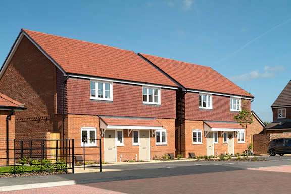 A red brick house with a black fence in front.