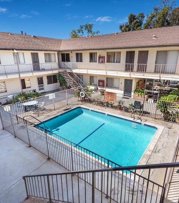 A pool with a hot tub and lounge chairs in front of a building.