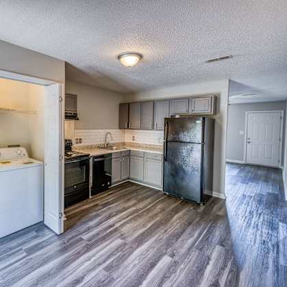 an empty kitchen with white appliances and a black refrigerator at Ashford Place Apartments, Kannapolis, NC