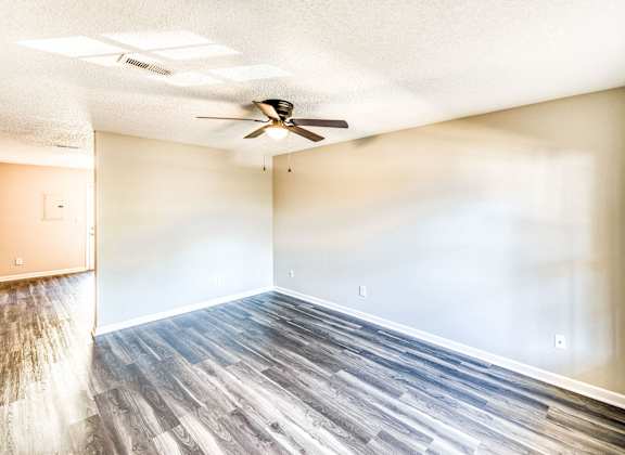 an empty living room with wood floors and a ceiling fan at Ashford Place Apartments, Kannapolis, NC