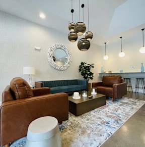 A living room with a brown leather sofa, a green couch, and a round mirror on the wall.