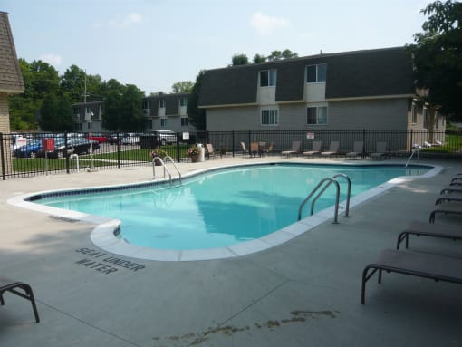 Outdoor swimming pool next to building with patio chairs