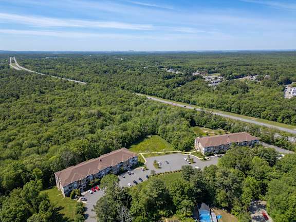 A bird's eye view of a large building surrounded by trees and a parking lot.