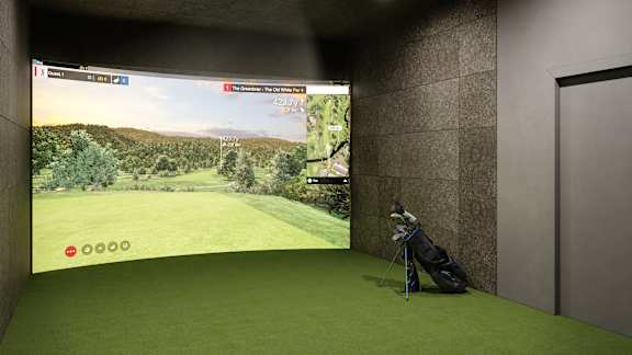 A golf simulator room with a screen showing a golf course.