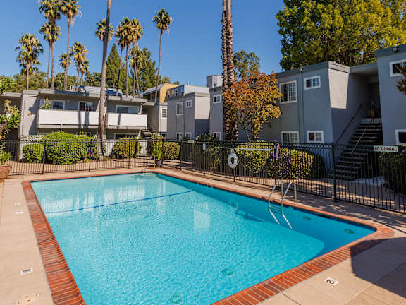 A swimming pool in front of a building with a black fence.