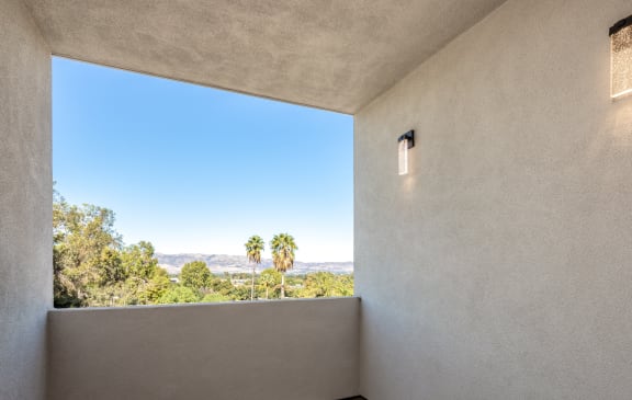 a room with a large window and a view of palm trees
