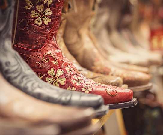 A row of shoes are lined up, the closest one is red with a flower design.