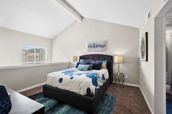 A bedroom with a bed, nightstand, and lamp.