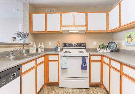 Fully equipped apartment kitchen with white stove and warm orange cabinetry at Waterbrook Apartments in Lincoln, Nebraska, professionally operated by Highlands Vista Group.