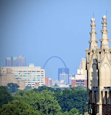 A cityscape with a large arch in the background and a building in the foreground.