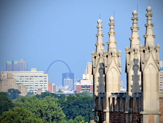 A cityscape with a large arch in the background and a building in the foreground.