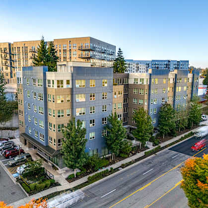 A street view of a residential area with apartment buildings and parked cars.