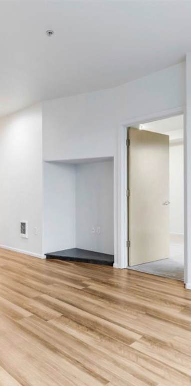A room with a white wall and a wooden floor.