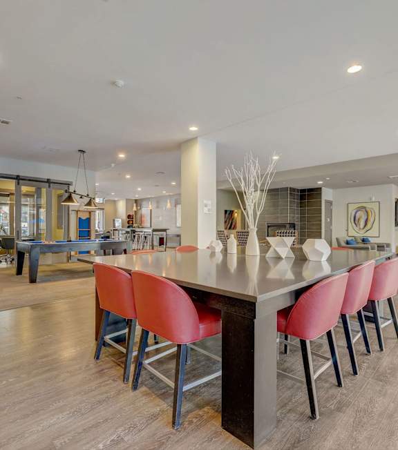 A modern kitchen with a long island and red chairs at Regatta Sloans Lake Apartments, Colorado, 80204