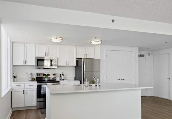 a kitchen with white cabinets and stainless steel appliances and a white counter top at The Zenith, Baltimore, Maryland