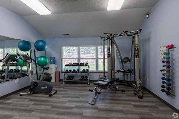 A gym with a variety of equipment including weights, a treadmill, and a bench press.