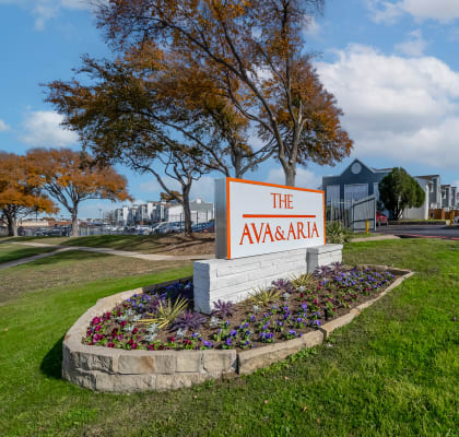 the avenue apartments sign in front of grass and flowers