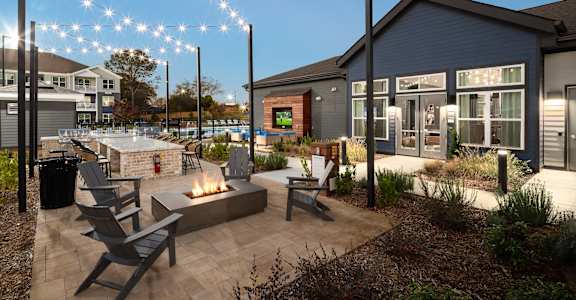 A patio area with a fire pit and chairs.
