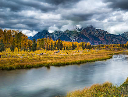 a river with trees and mountains in the background