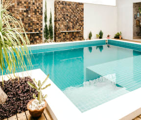 a swimming pool is surrounded by a wooden deck and a plant