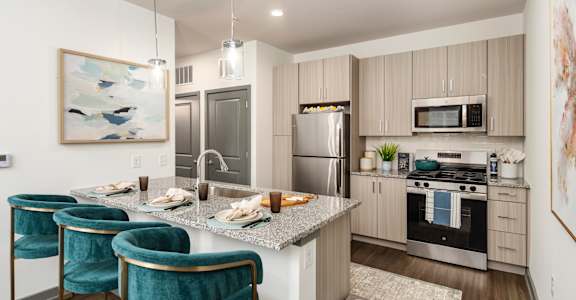 a kitchen with a marble counter top and a island with three chairs
