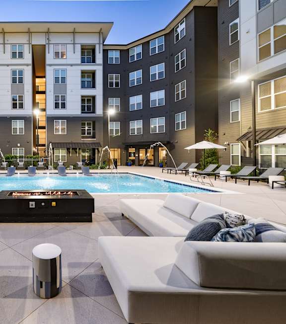 A large outdoor pool surrounded by lounge chairs and umbrellas.