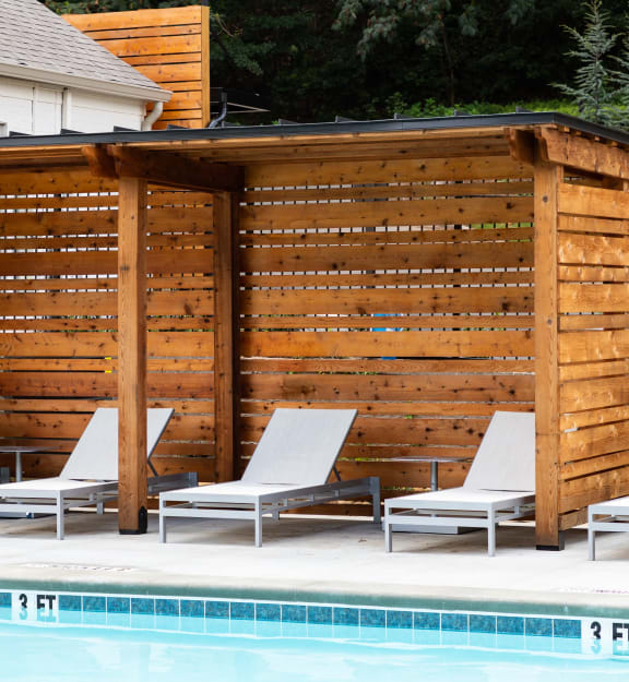 a wooden pool deck with chairs next to a swimming pool