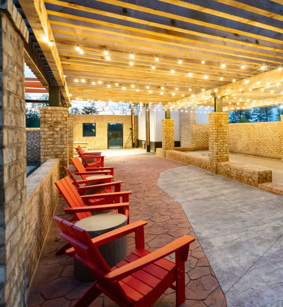 a row of red chairs on a patio under a wooden structure