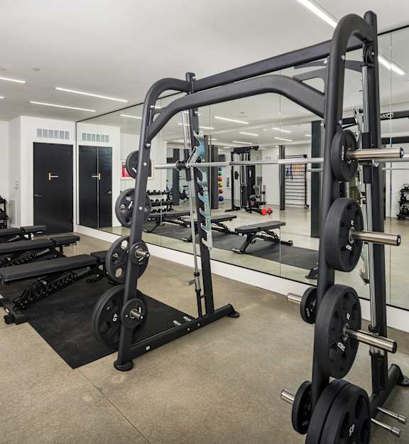 A gym with a variety of equipment including weightlifting machines and benches.