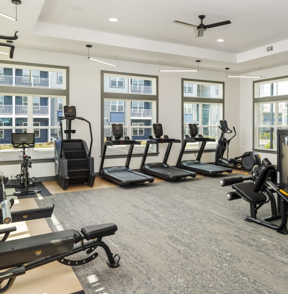 a gym with treadmills and other exercise equipment in a building with windows