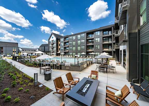 A modern outdoor seating area with wooden chairs and tables.