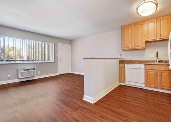 an empty living room and kitchen with wood flooring and a window