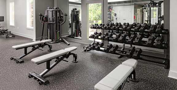A gym with a variety of equipment including weights and benches.