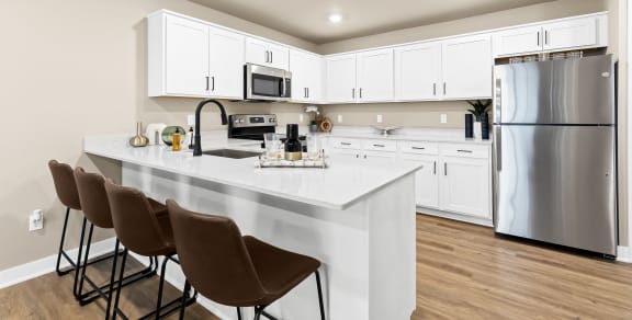 an open kitchen with a large island and stainless steel refrigerator
