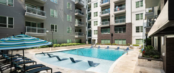 an outdoor pool with lounge chairs and an apartment building