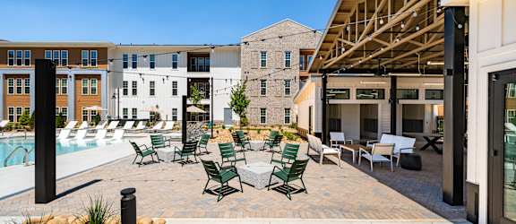 A poolside area with chairs and a building in the background.