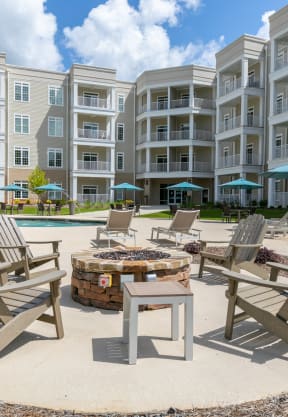 an outdoor patio with chairs and a fire pit in front of an apartment building at The Station at River Crossing, Macon