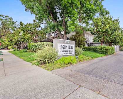 Fremont, CA Apartments - Logan Park - Property Sign At Entrance Near Lots Of Greenery