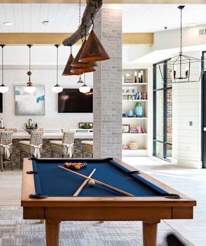 A billiard table is in the middle of a room with a white and wood floor.