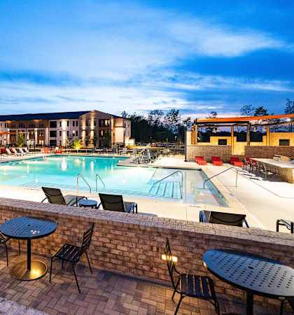 a swimming pool with tables and chairs at night