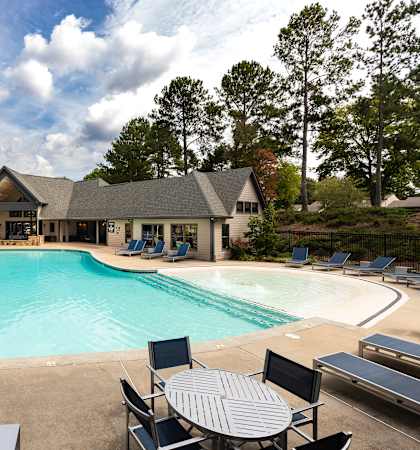 A large outdoor swimming pool surrounded by lounge chairs and umbrellas.