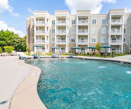 a large swimming pool with an apartment building in the background at The Station at River Crossing, Macon, GA