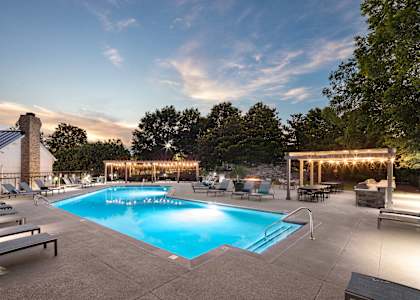 A large outdoor swimming pool surrounded by lounge chairs and trees.