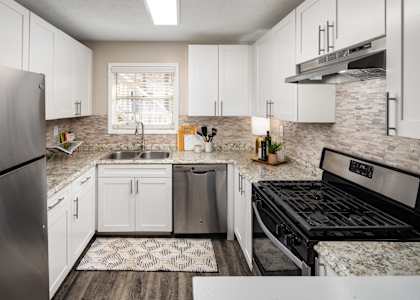 an updated kitchen with white cabinets and stainless steel appliances
