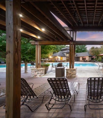 a covered patio with chairs and a swimming pool