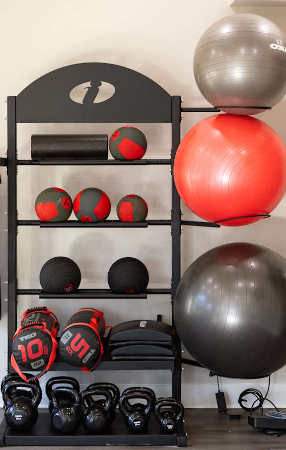 a workout room with two balls and a rack with weights and dumbbells